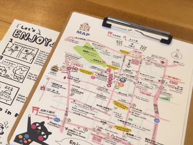 Our hand-drawn neighbourhood map on a clipboard, next to a comic guide to the public bath