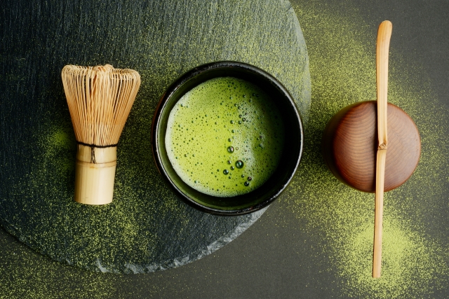 A bowl of matcha and a small wagashi sweet on a wooden tray in a quiet Kyoto tea shop