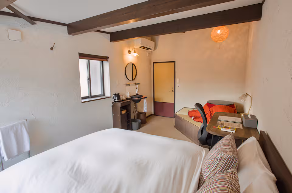 Aka room with a double bed, a desk, a washbasin and a raised tatami corner with a kotatsu