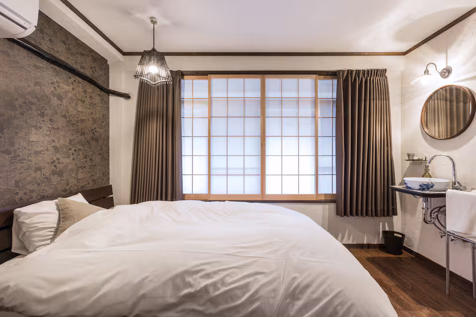 Kuro room with a double bed, a shoji window and a small washbasin with a round mirror
