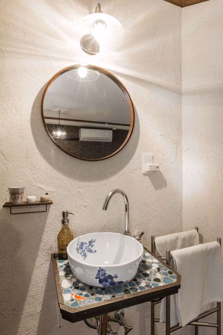 Kuro room's washbasin: a blue-and-white porcelain bowl on a mosaic stand under a round mirror