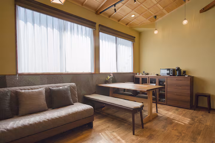 Sane cottage living room with a sofa, a wooden dining table and bench under a coffered ceiling
