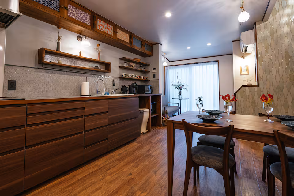 Tane cottage kitchen and dining table, with a sunny window seat beyond